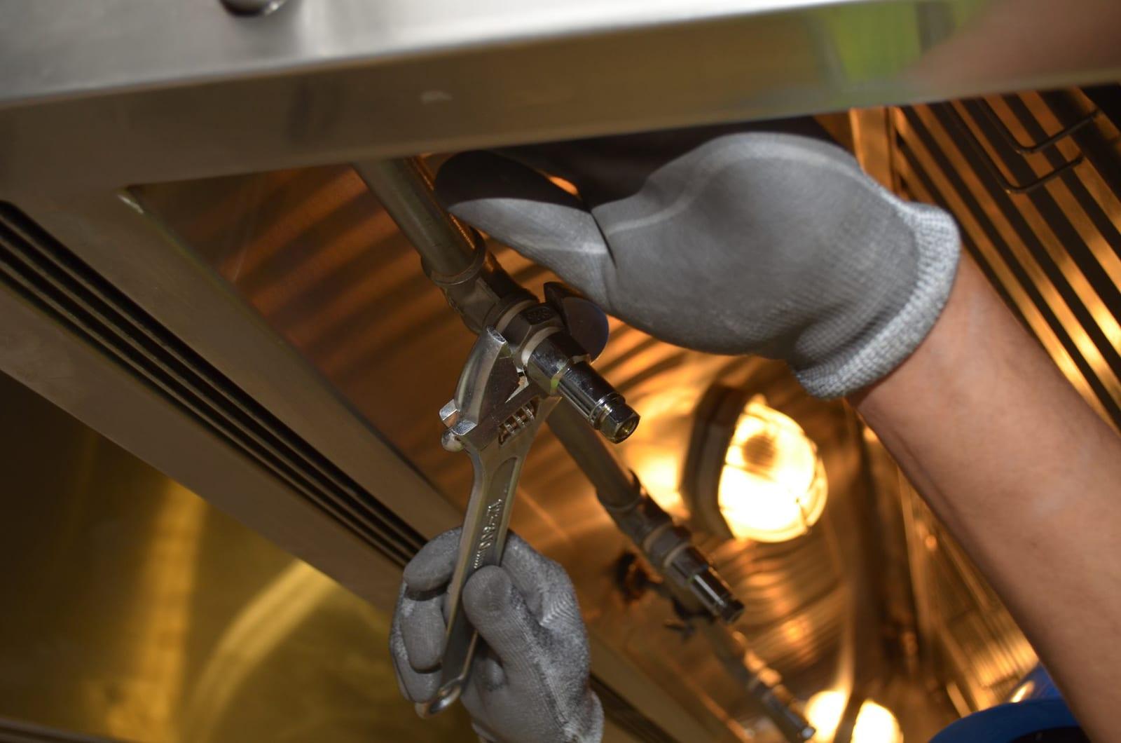 Operario de MJ Serveis Integrals reparando una instalación con llave inglesa